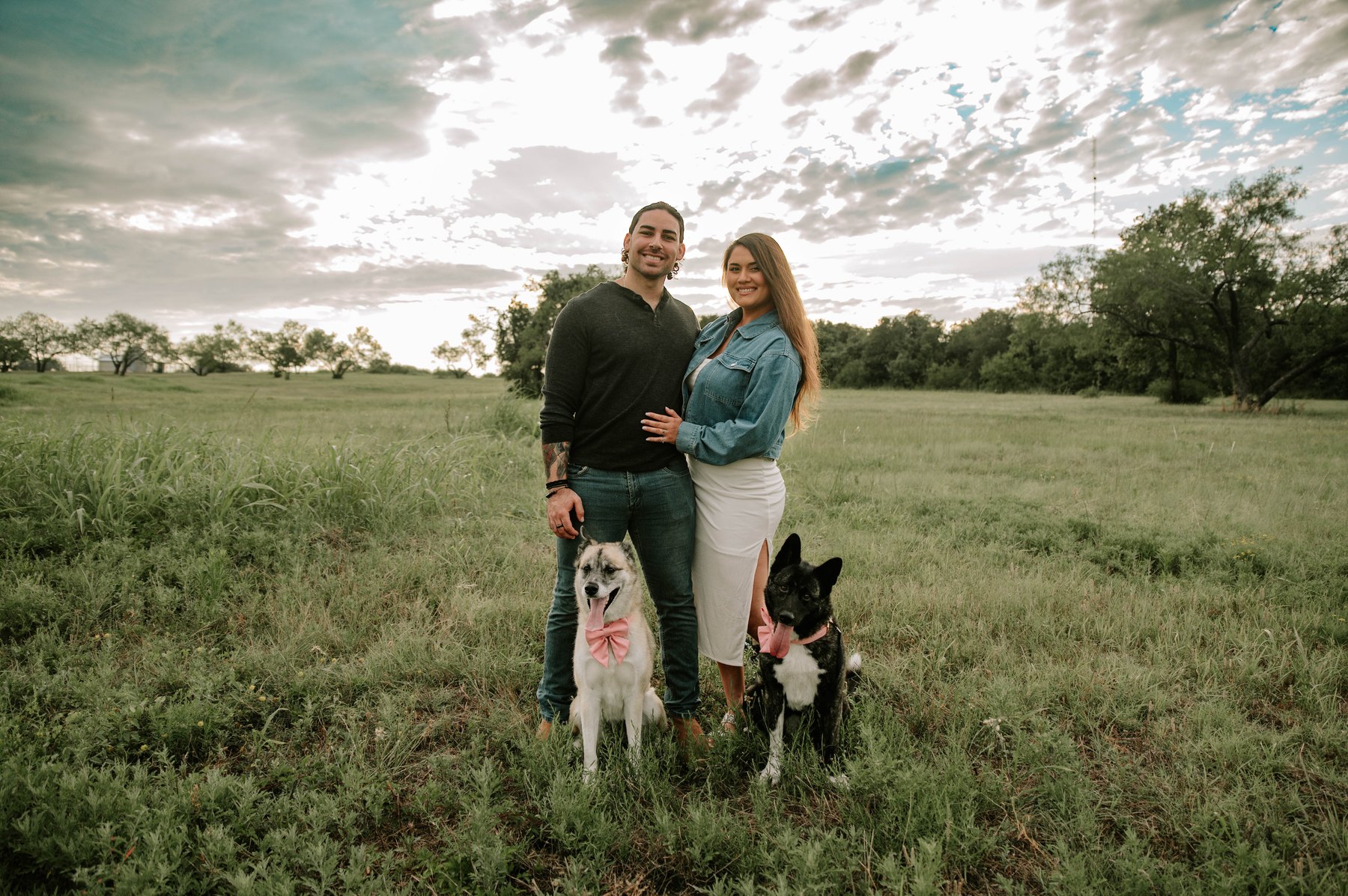 Ian with his wife and their dogs in a Texas field at sunset